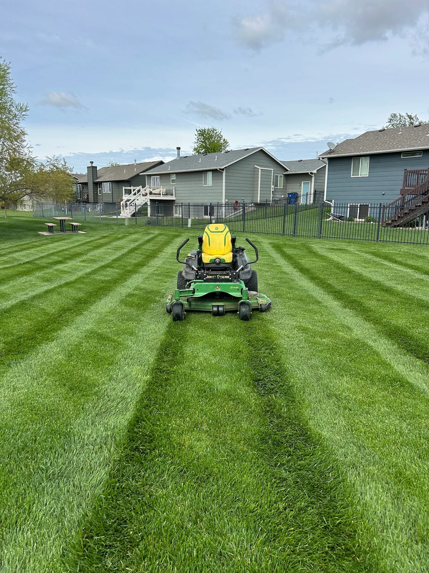 Zero-turn mower creating striped lawn mowing pattern on residential grass yard