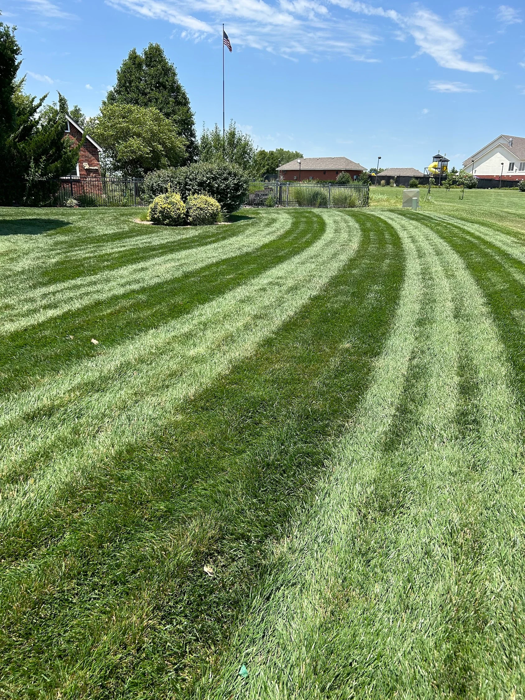 Striped lawn mowing pattern on residential property with maintained landscape beds