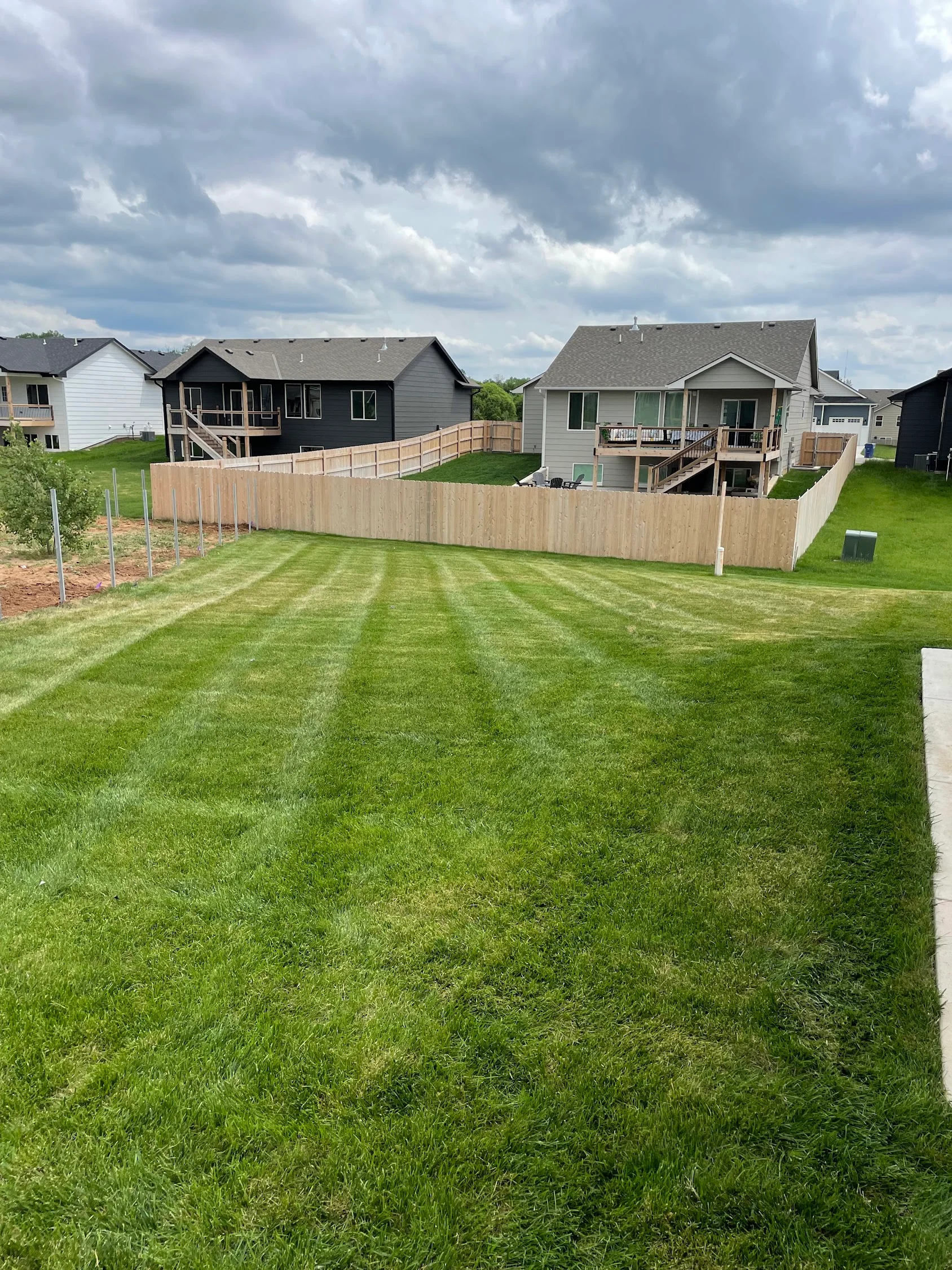 Striped lawn with privacy fencing, mulch beds, and maintained residential yard
